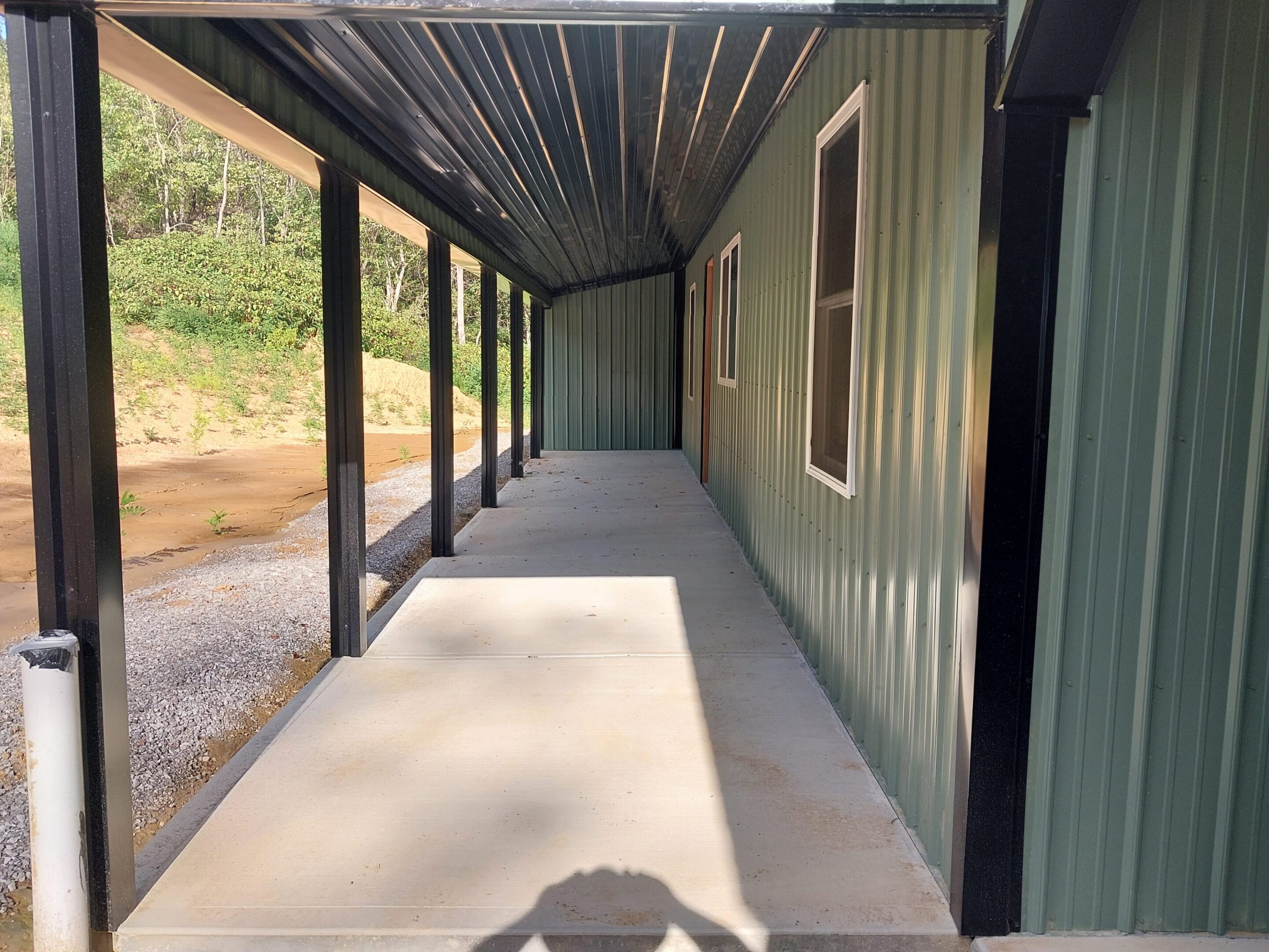 Covered concrete walkway beside green metal building