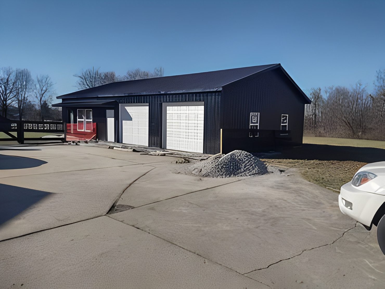 Black metal garage building with two white doors