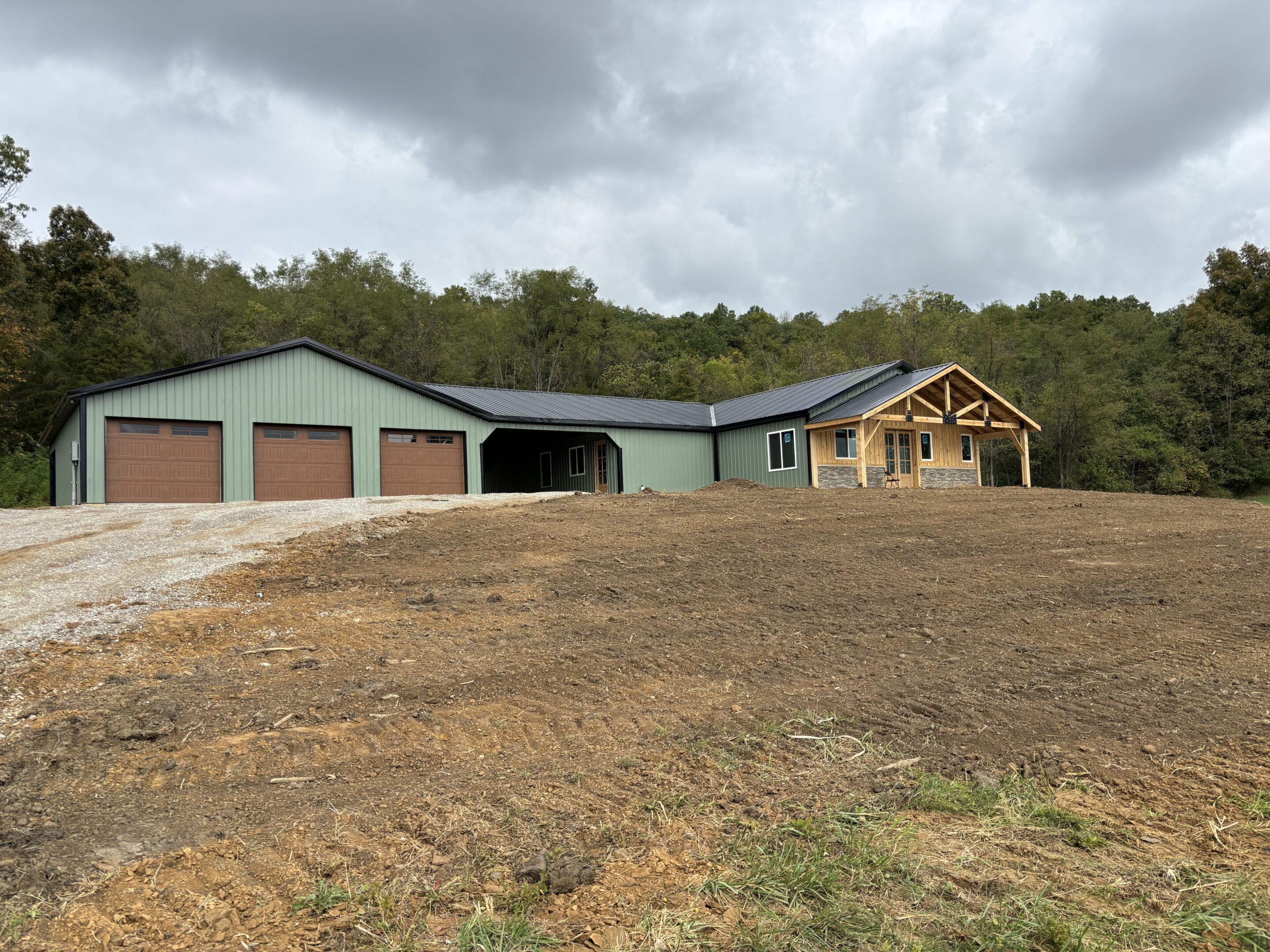 Green metal home with three garages and porch