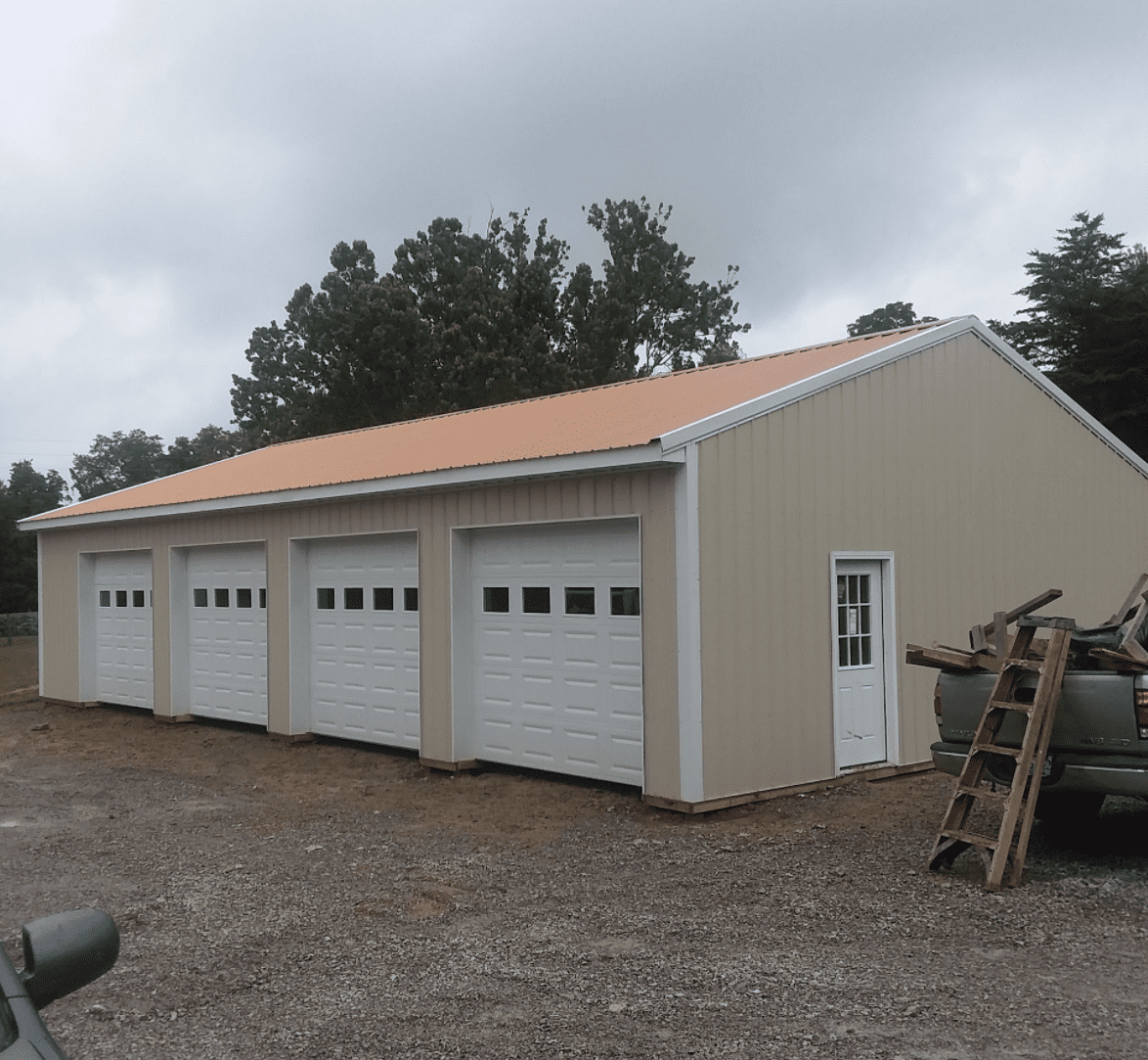 Four bay beige metal garage with gravel driveway