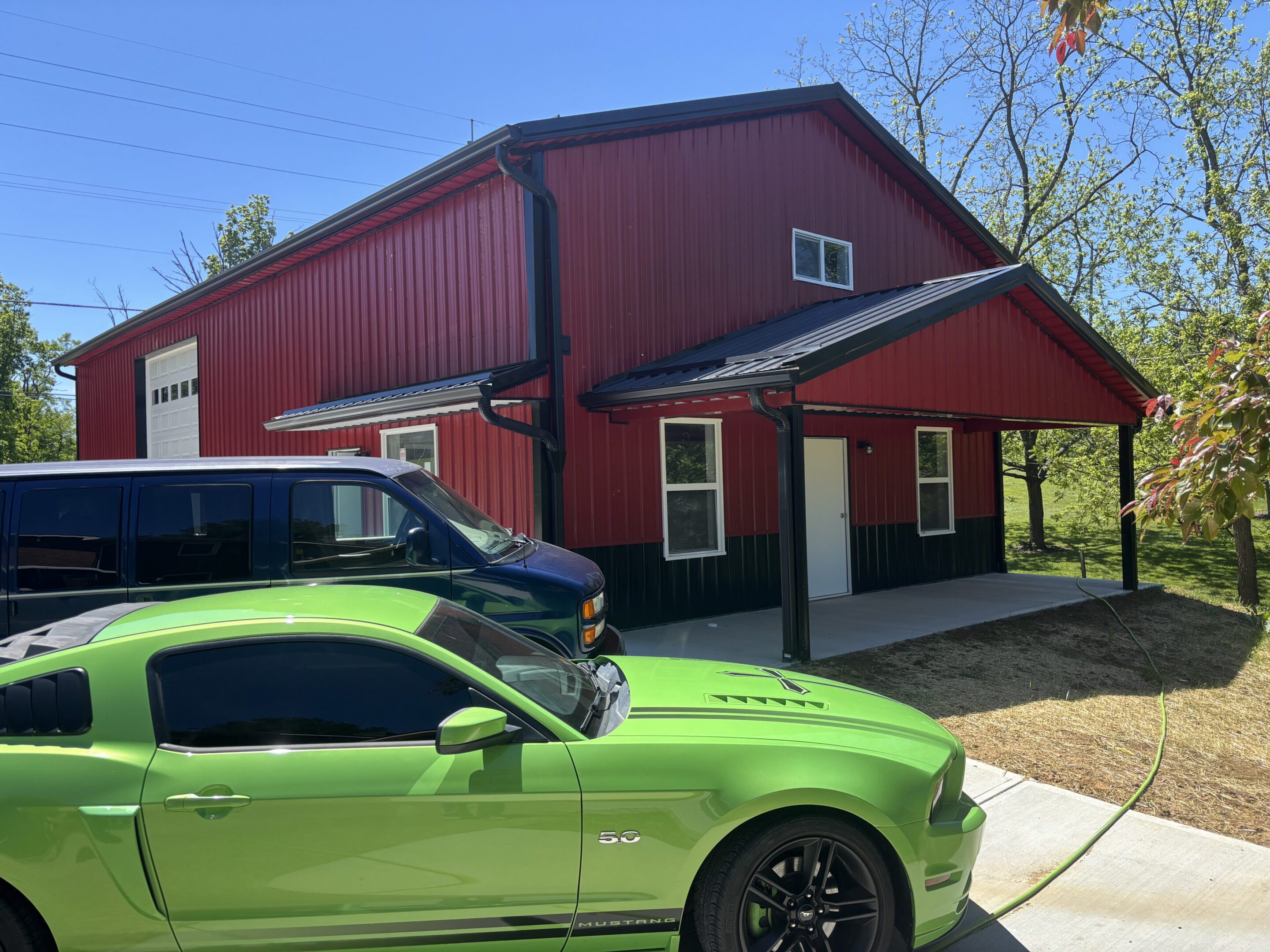 Green Mustang parked by red metal garage
