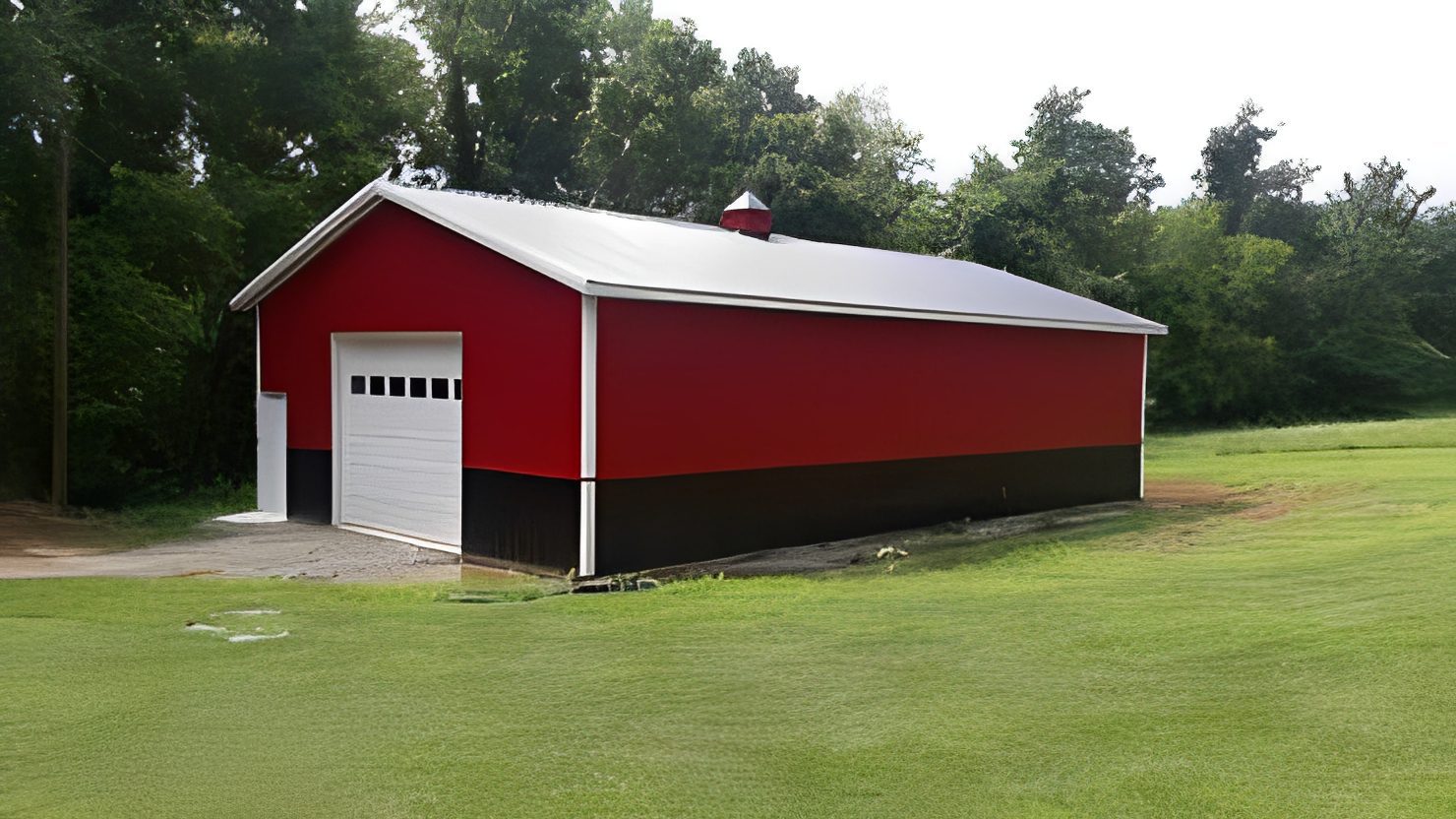 Red barn with white garage door on lawn
